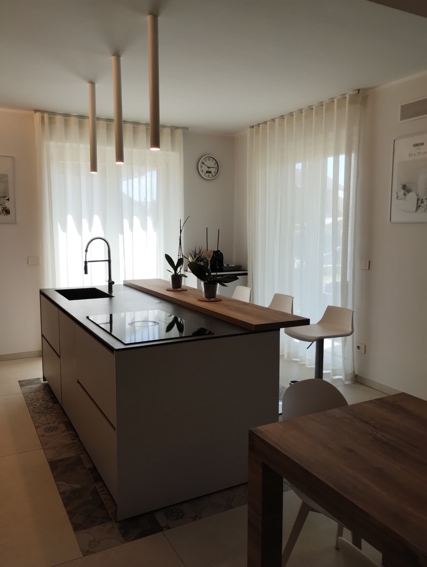 Cucina contemporanea illuminata da tendaggi bianchi trasparenti
